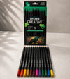 A 12-pack of Chigaro Creative colored pencil set, with the black retail box standing upright behind twelve loose pencils arranged in a row. The pencils feature various vibrant colors on their tips, including red, orange, yellow, brown, green, blue, and purple, set against a neutral light gray background with soft leaf shadows.